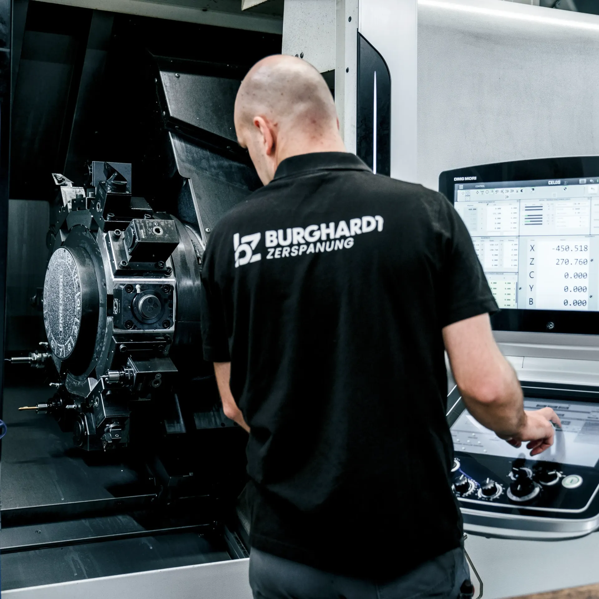 Eine Person mit Handschuhen untersucht eine Metallstange an einer CNC-Maschine.