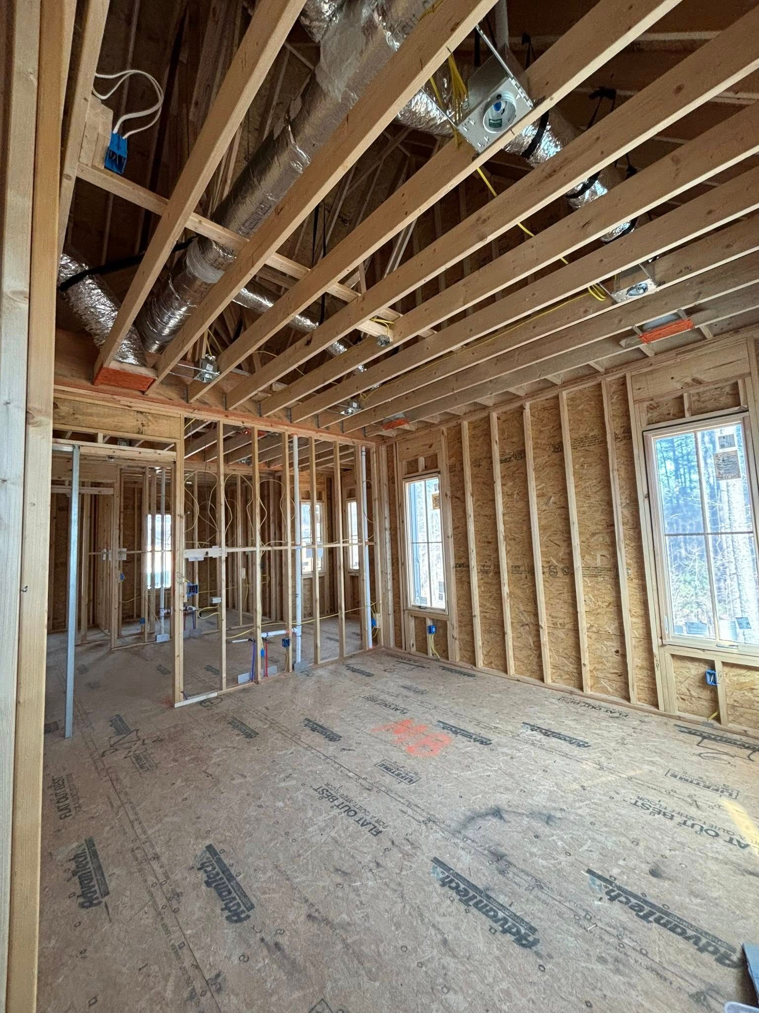 A room in a house under construction with wooden beams and windows.