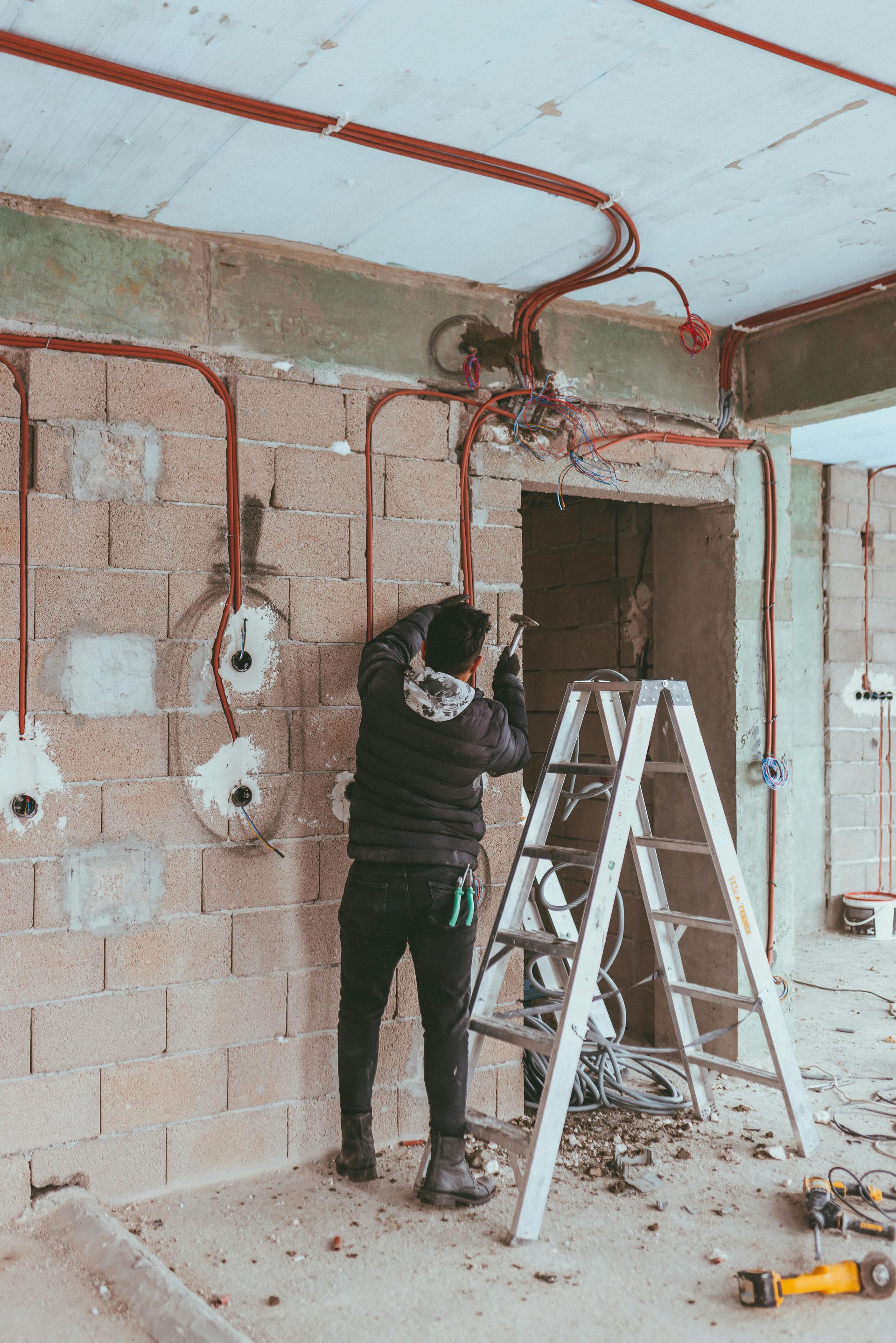 A man is standing on a ladder working on a wall.