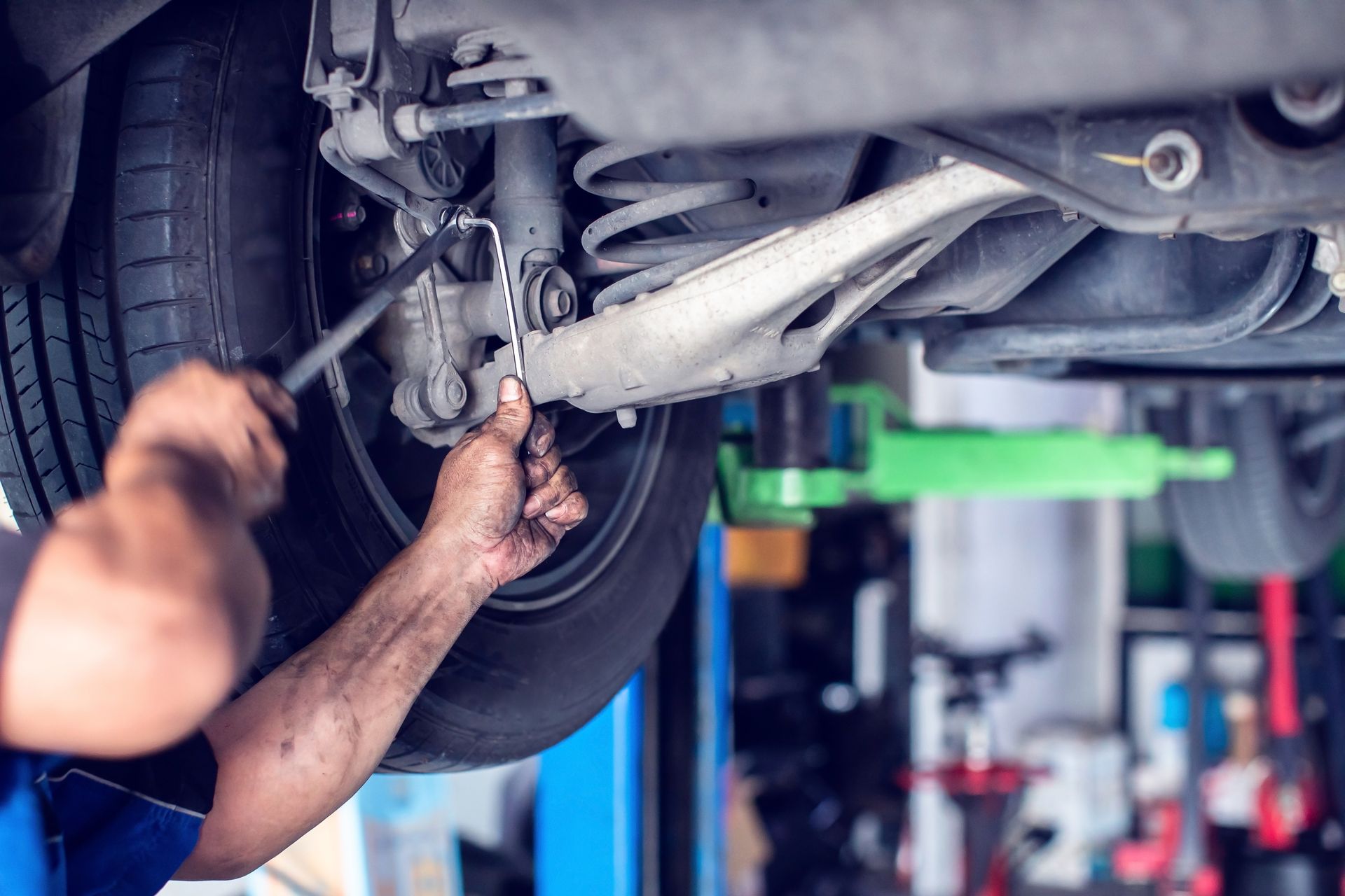 Mechanic working under a raised car in an auto repair shop Mechanic working under a raised car in an auto repair shop