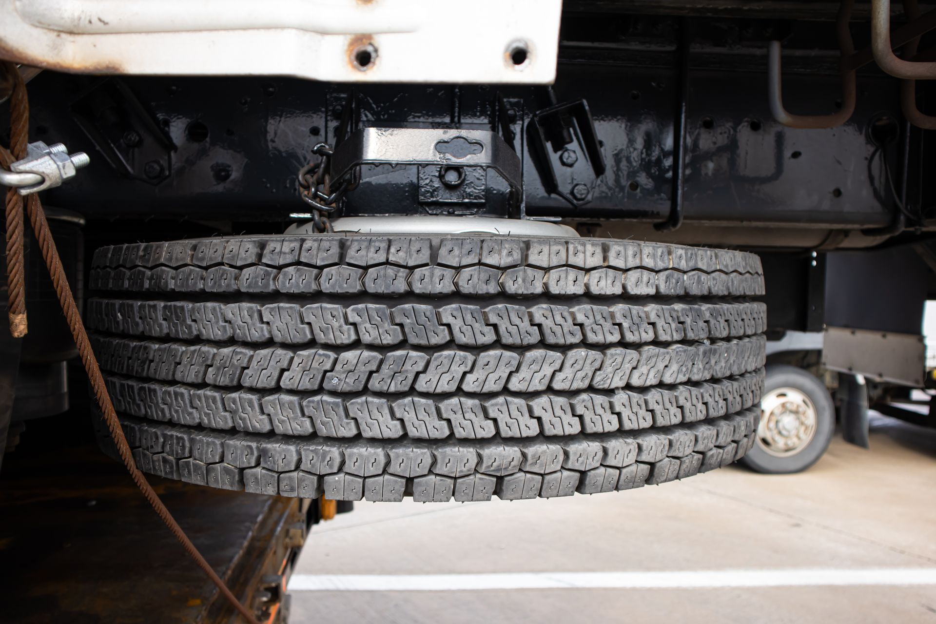 Undercarriage view of a truck with a spare tire mounted beneath the chassis and another vehicle in the background Undercarriage view of a truck with a spare tire mounted beneath the chassis and another vehicle in the background