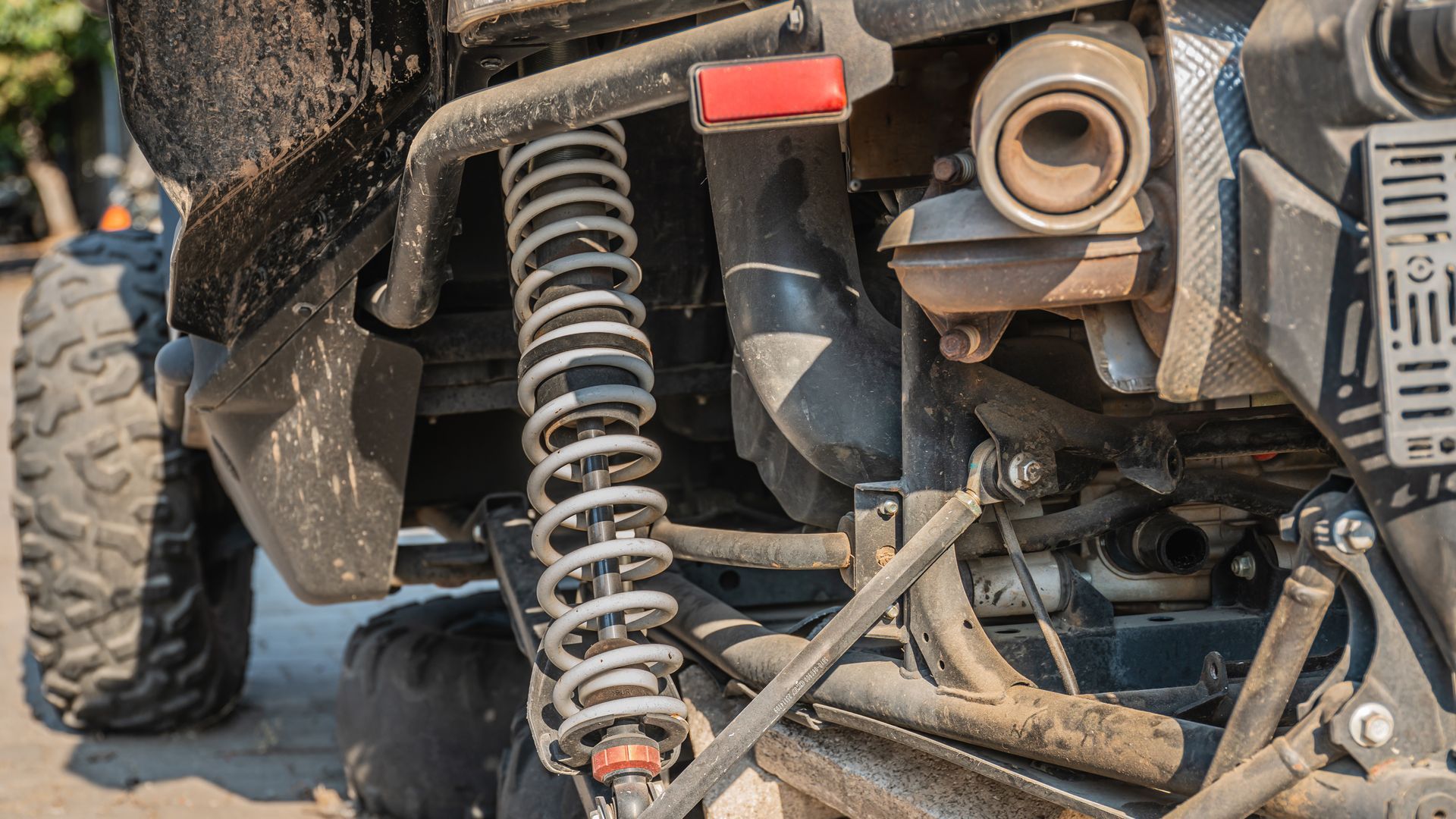 Close-up of an off-road vehicle’s suspension and tire with dust and mechanical components visible Close-up of an off-road vehicle’s suspension and tire with dust and mechanical components visible