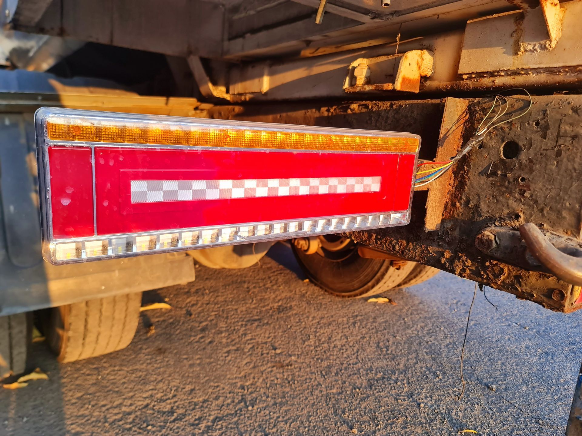 Red rectangular reflective panel on the rear side of a truck or trailer, with wheels visible underneath. Red rectangular reflective panel on the rear side of a truck or trailer, with wheels visible underneath.