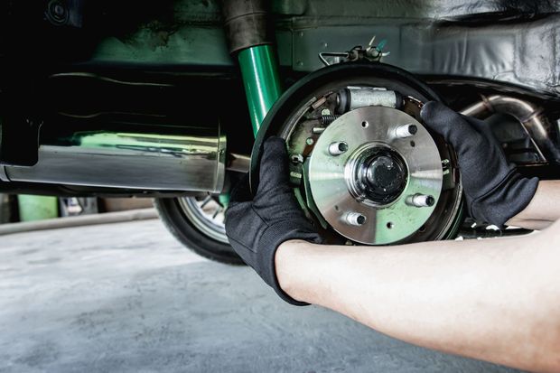 Hands installing a car brake assembly under the vehicle Hands installing a car brake assembly under the vehicle