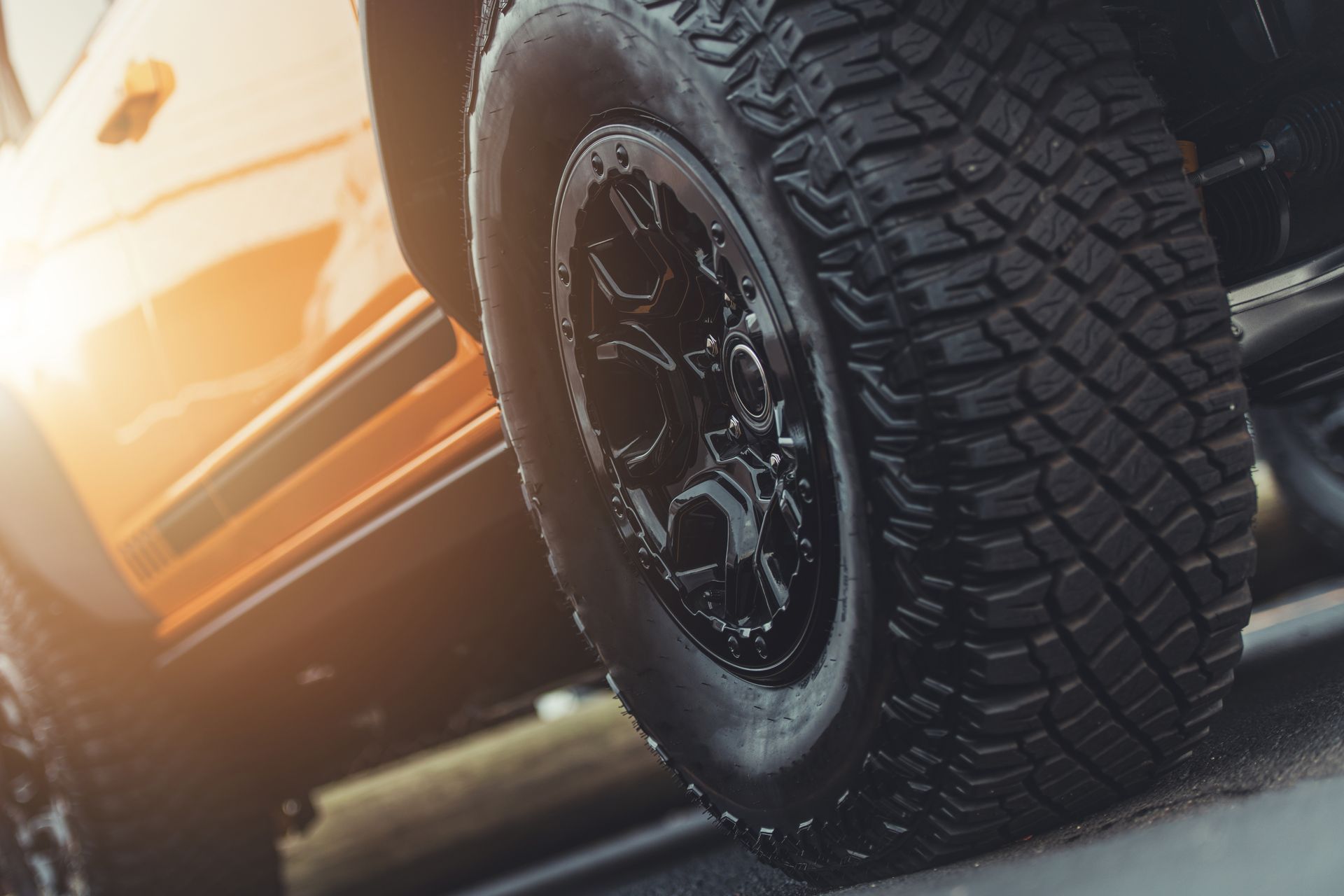 Close-up of an off-road vehicle tire on a dirt road at sunset Close-up of an off-road vehicle tire on a dirt road at sunset