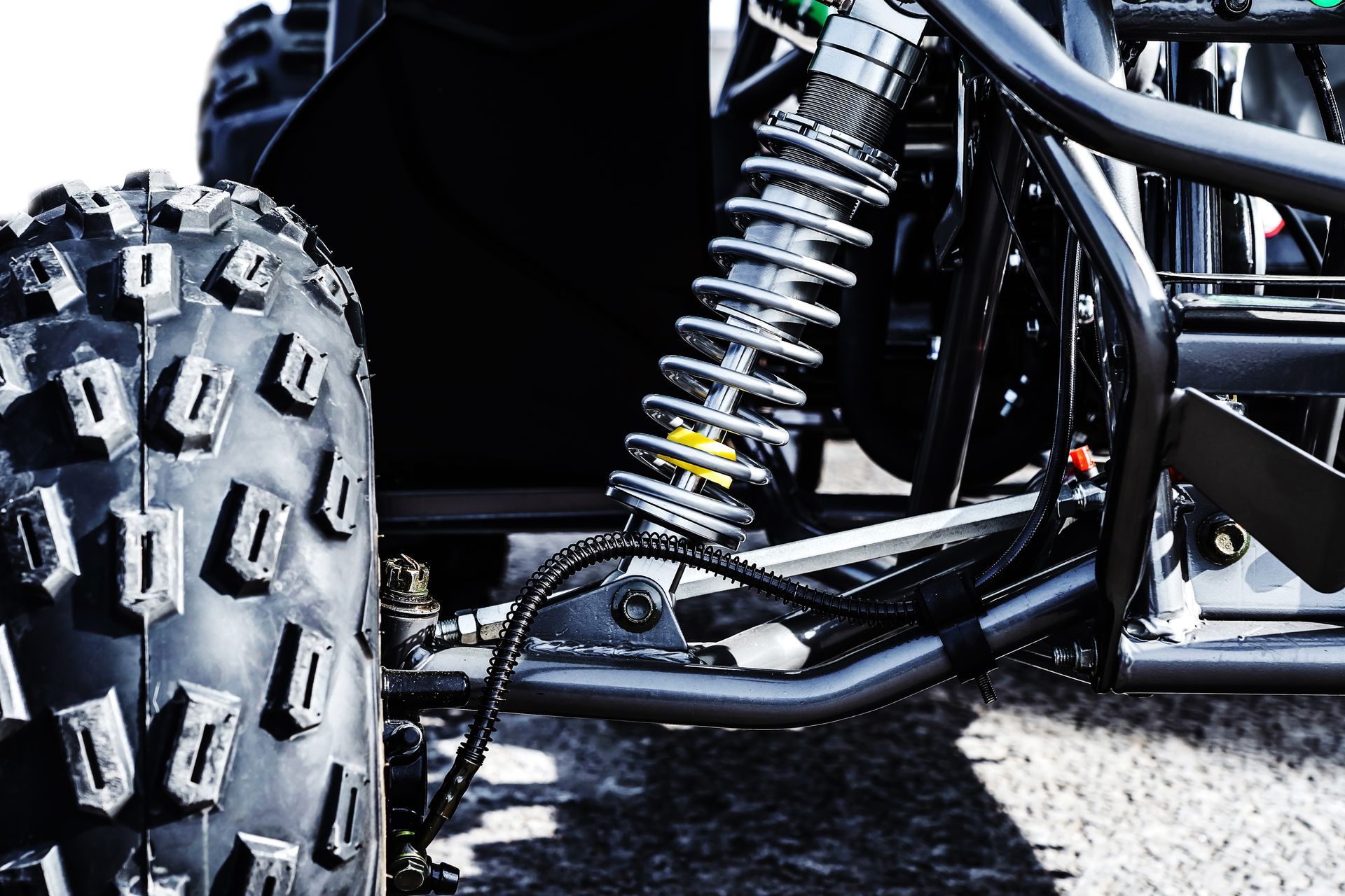Close-up of an off-road vehicle’s front wheel and suspension on a rocky surface Close-up of an off-road vehicle’s front wheel and suspension on a rocky surface