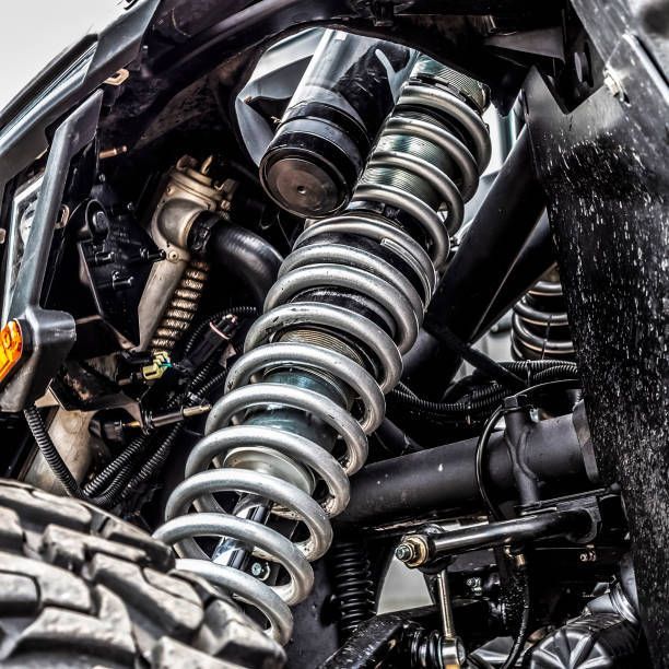 Close-up of a black vehicle suspension with a coiled spring and shock absorber.
