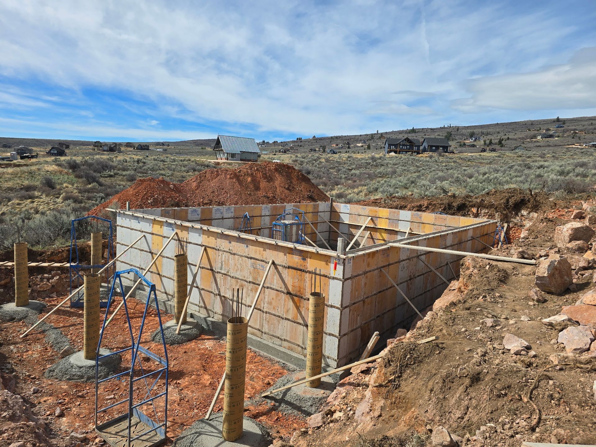 Concrete foundation under construction with rebar and wooden forms in a rocky desert landscape
