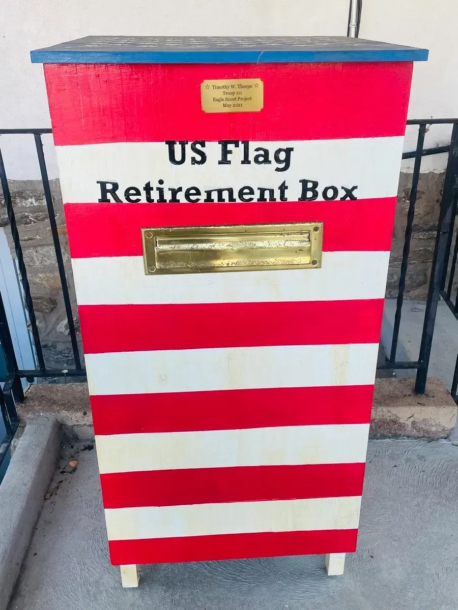 US flag retirement box painted with red and white stripes and a gold plaque