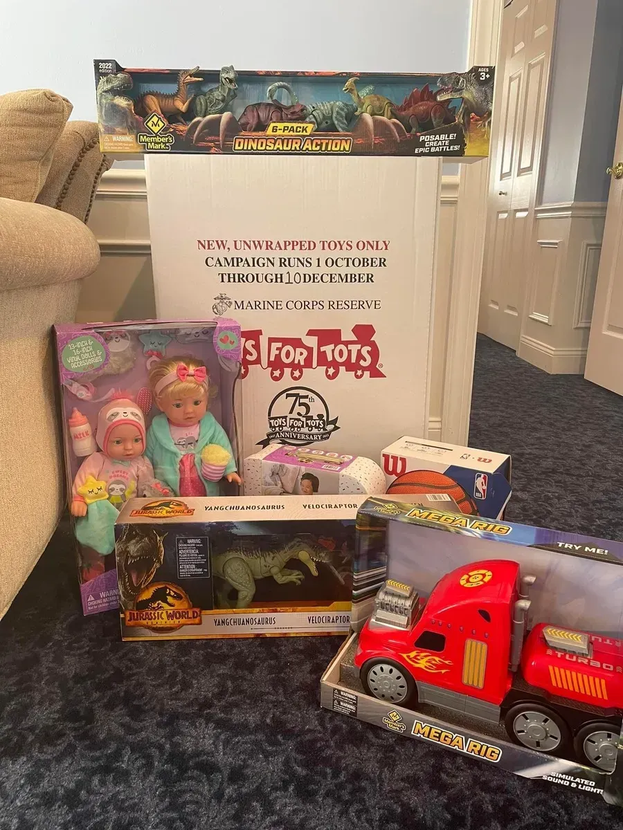 Toy donation display with boxes of dolls, a red truck, and a