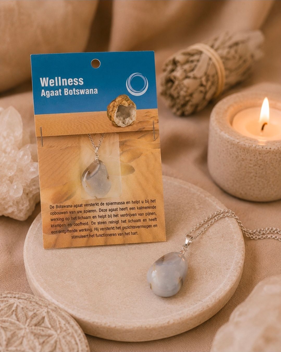 Een wellness-edelstenenketting in een blauw-beige verpakking, naast een brandende kaars op een beige dienblad.
