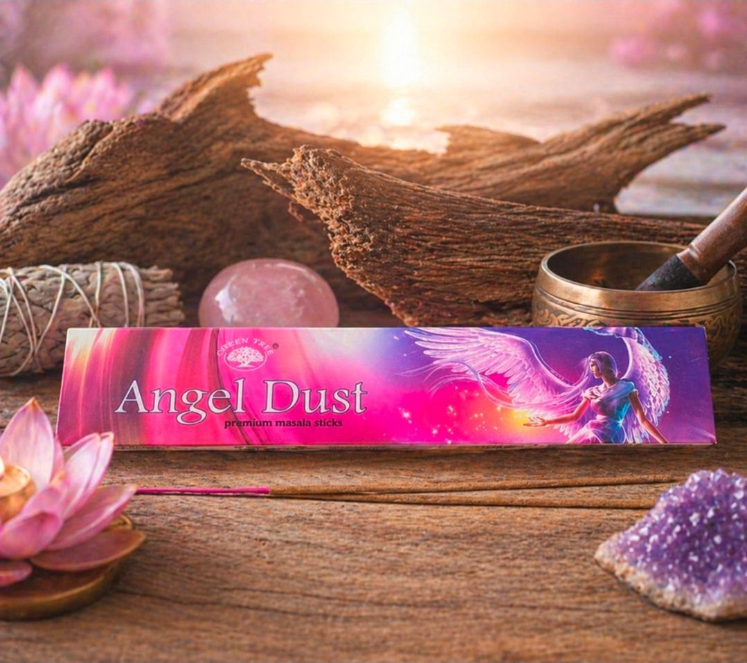 Een doosje Angel Dust wierook op een houten tafel met roze bloemen, een bosje salie en een cluster kristallen.