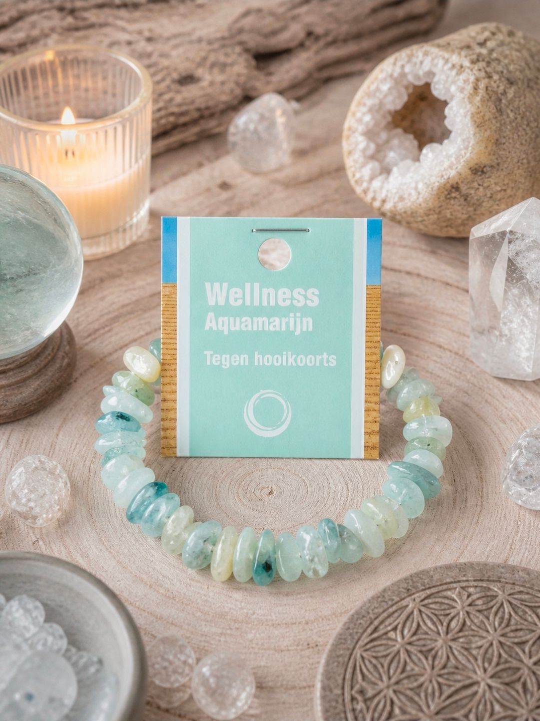 Wellness-sieraden en kristallen decoratie op een zachtbeige ondergrond met een brandende kaars en een geode.