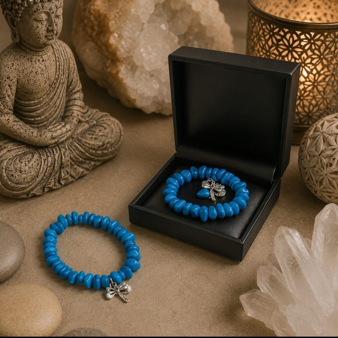 Blauwe kralenarmband in een open zwarte doos, naast een bijpassende armband op een beige ondergrond met Boeddhabeeldjes.