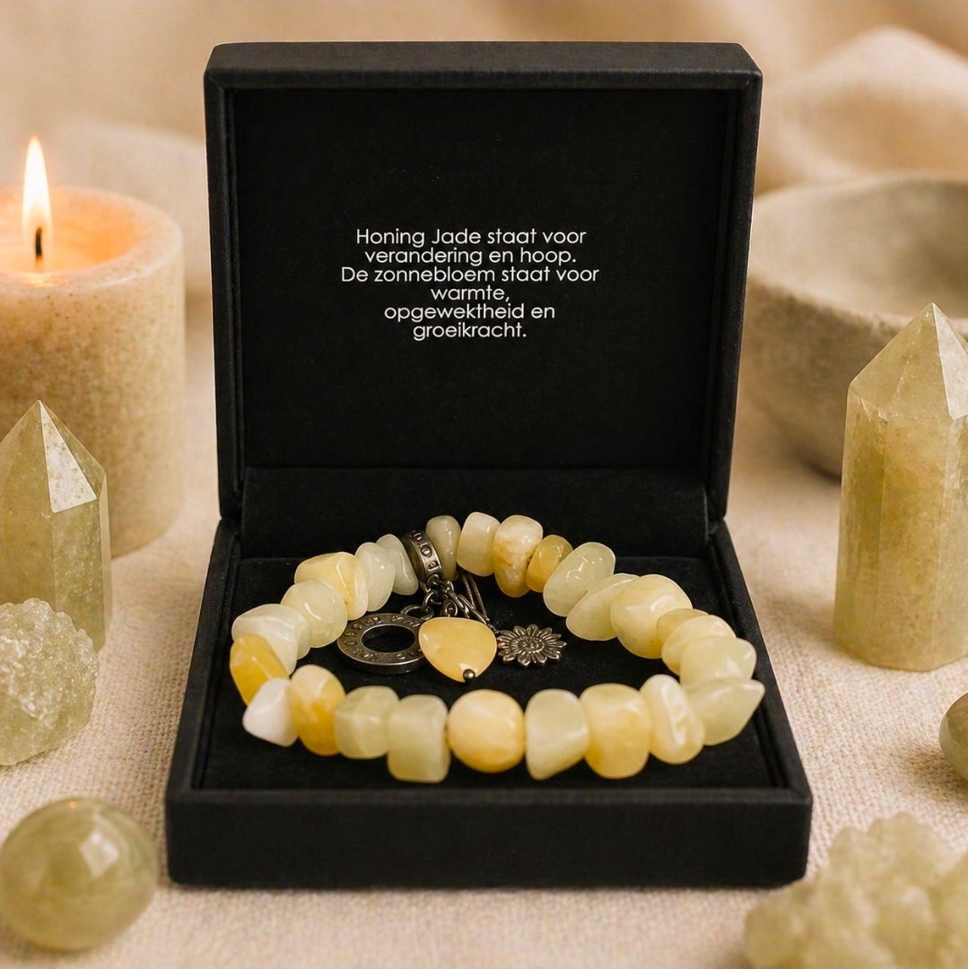 Zwarte geschenkdoos met daarin twee kralenarmbanden en kaarsen in een warme beige omgeving.