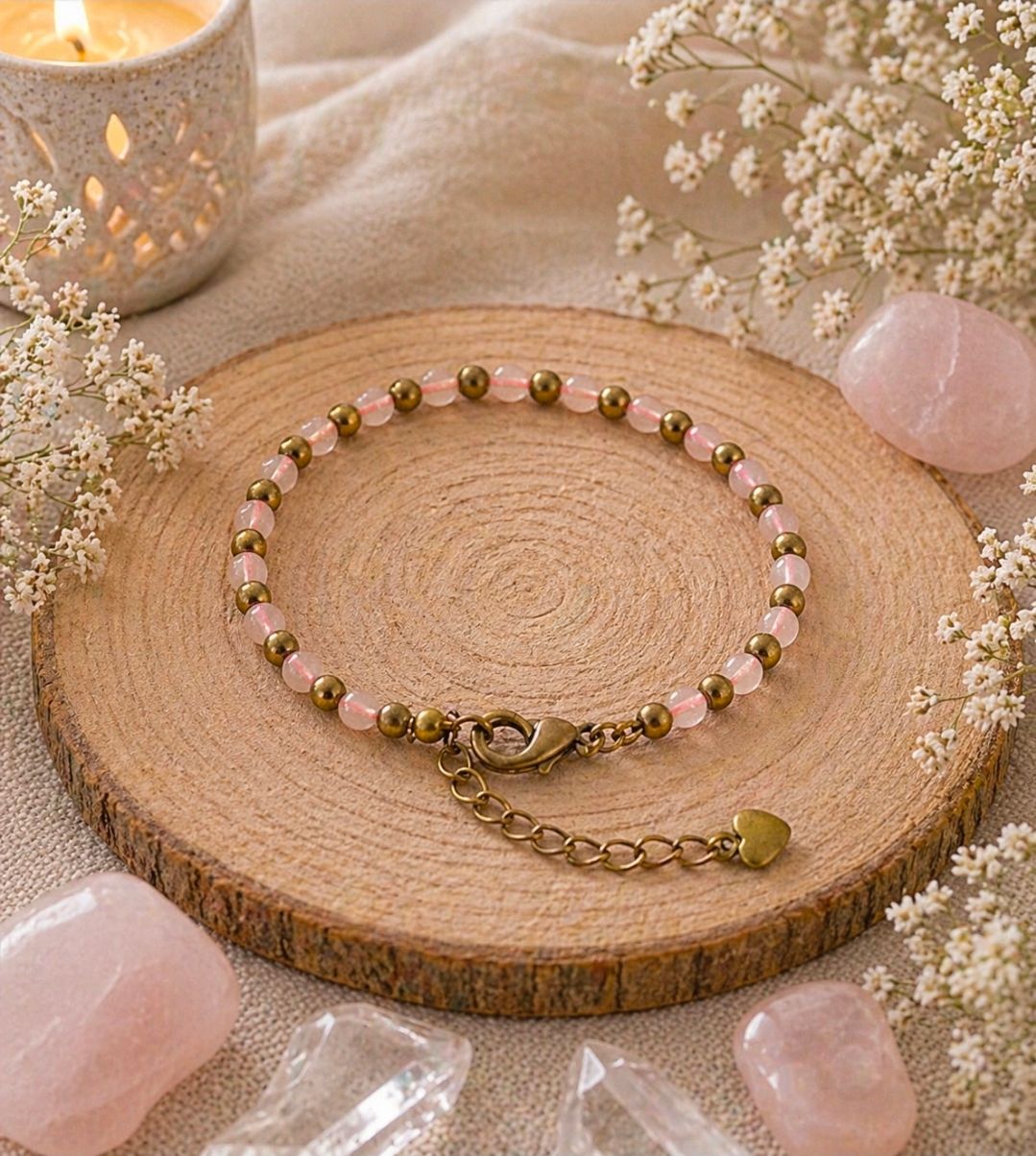 Een kralenarmband op een houten schijfje met roze steentjes en bloemen, naast een brandende kaars.