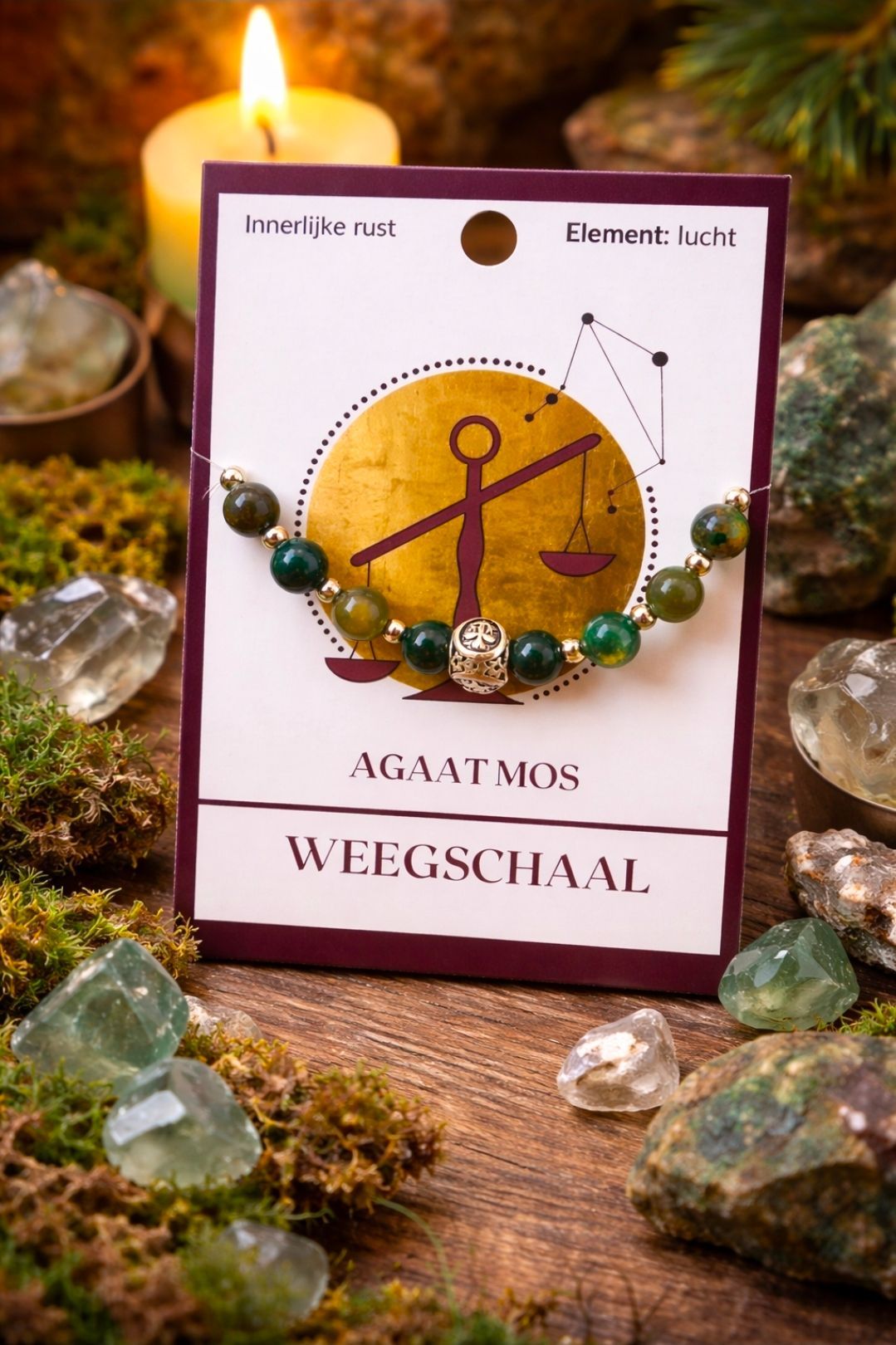 Een brandende kaars naast een agaat mala-kaart en een groene kralenarmband op een rustieke houten ondergrond.