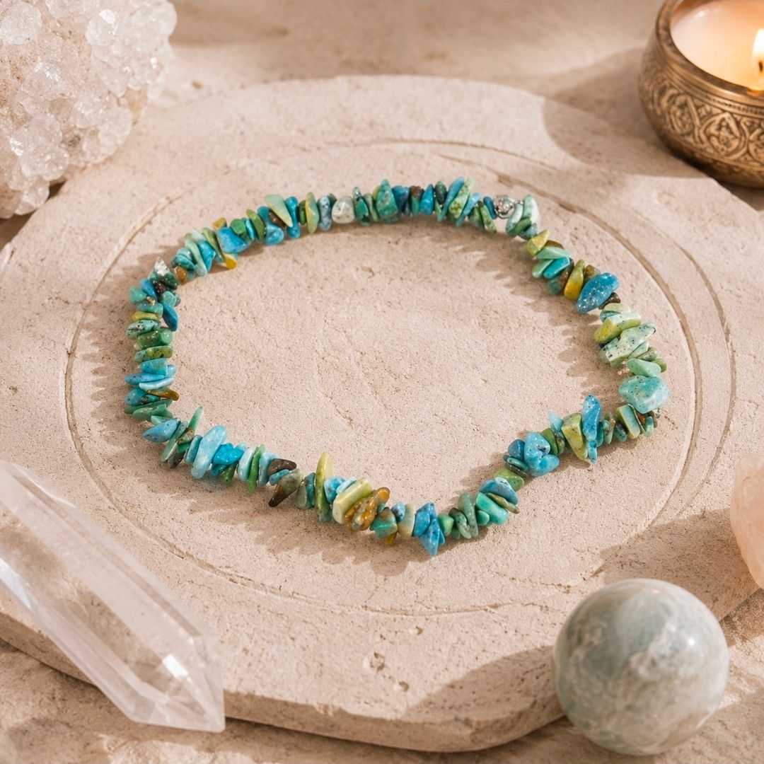 Armband van turkooizen en gele stenen kralen op een beige ondergrond met kristallen en een ronde edelsteen.