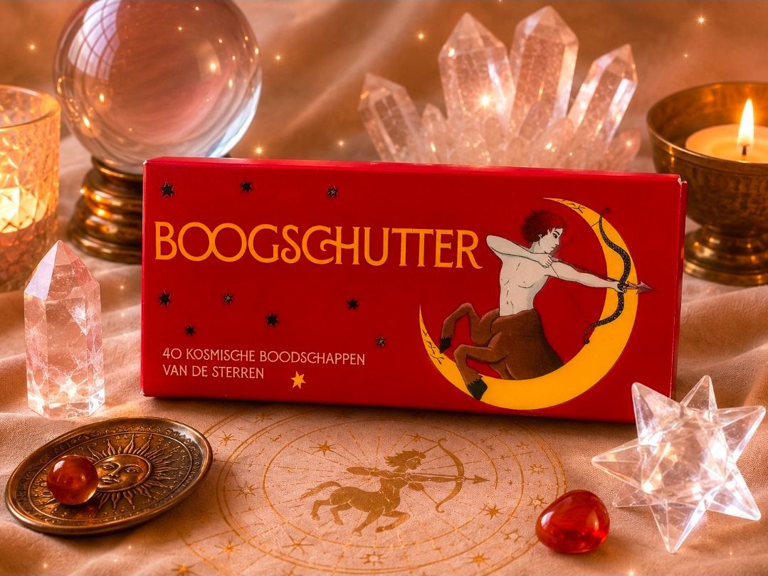 Rode BOOGSCHUTTER productdoos met sterrenmotief en een gouden boogschutter op een feestelijk verlichte tafel.