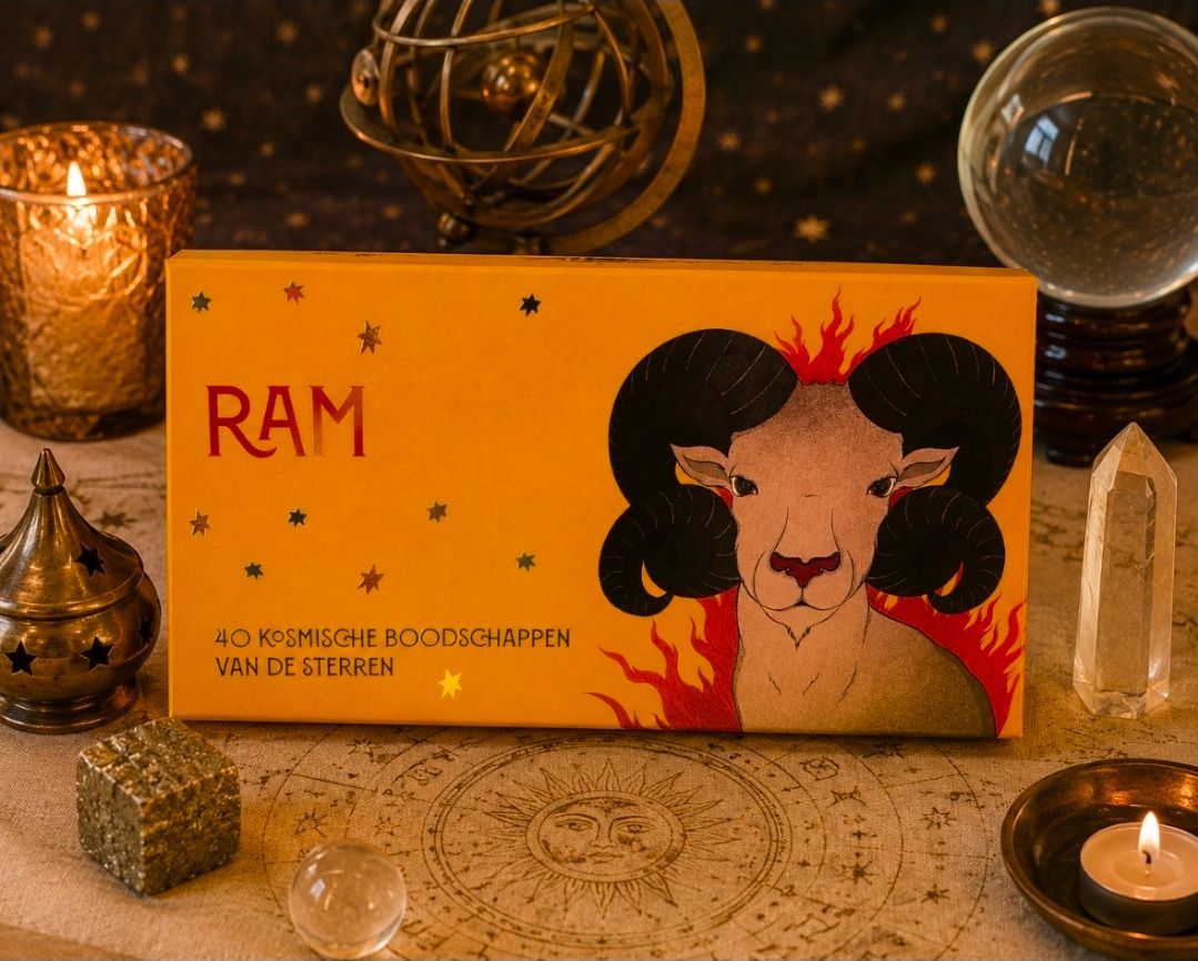 Gele RAM-doos met een afbeelding van een zwarte ram en kaarsen op een tafelkleed met patroon.