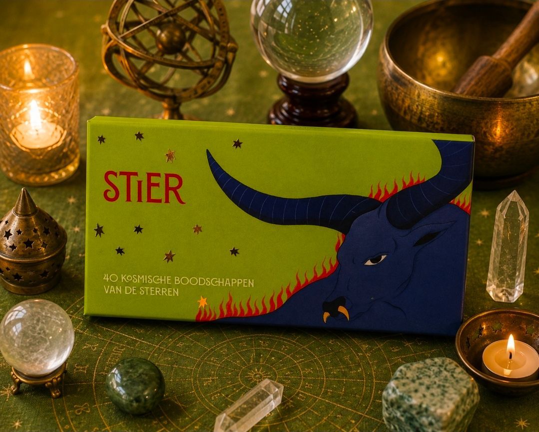 Groene STIER-doos met een afbeelding van een blauwe stier, omringd door kaarsen en kristallen op een groene doek.