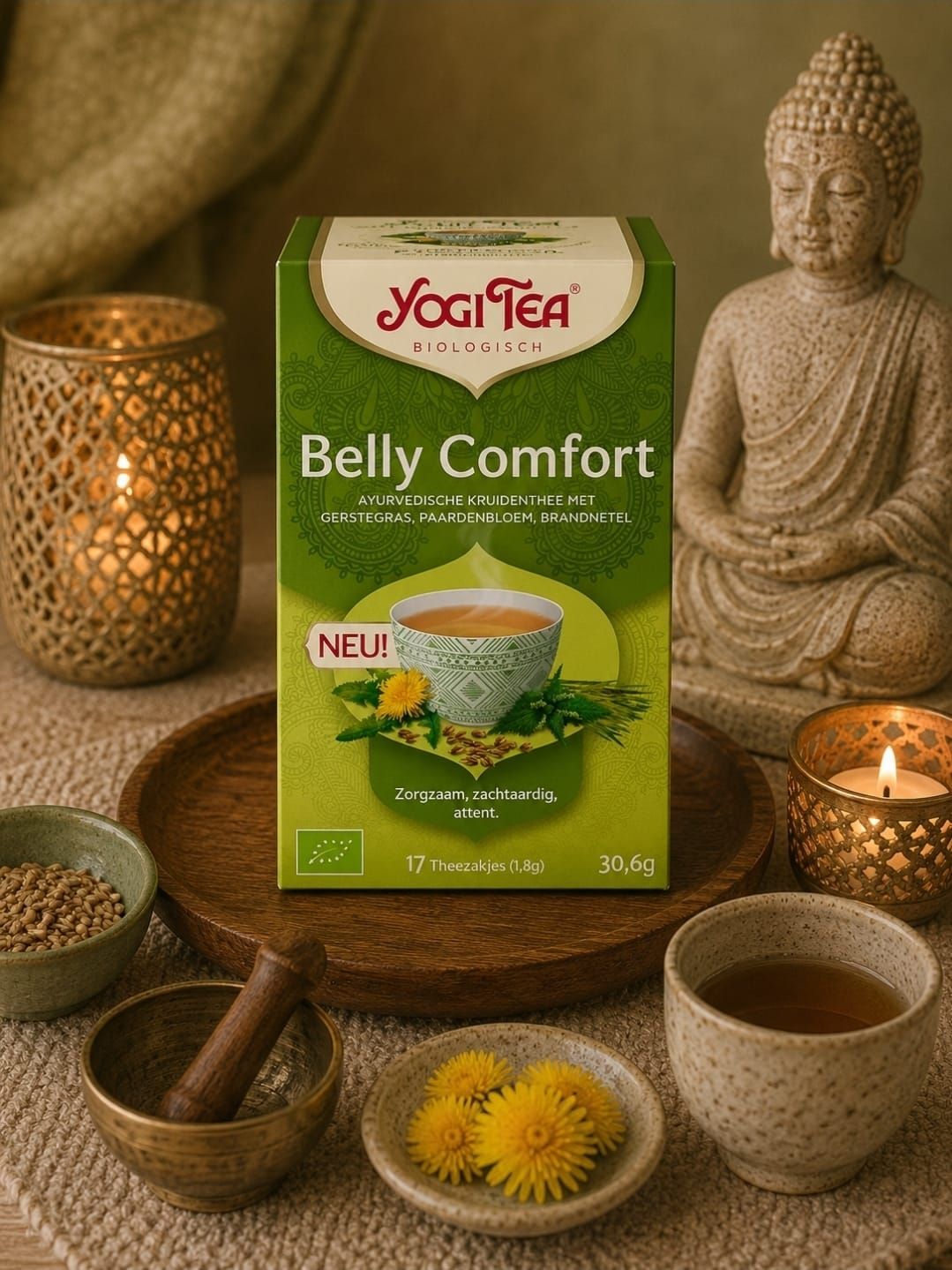 Yogi Tea Belly Comfort-box op een warme tafel met kaarsen, een Boeddhabeeldje, een theekom en bloemen.