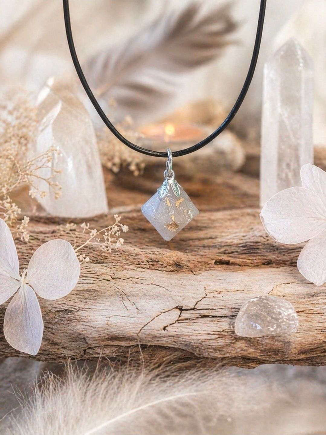 Zwarte koordketting met kristallen hanger aan een rustieke houten koord met zachtbeige decoratie.