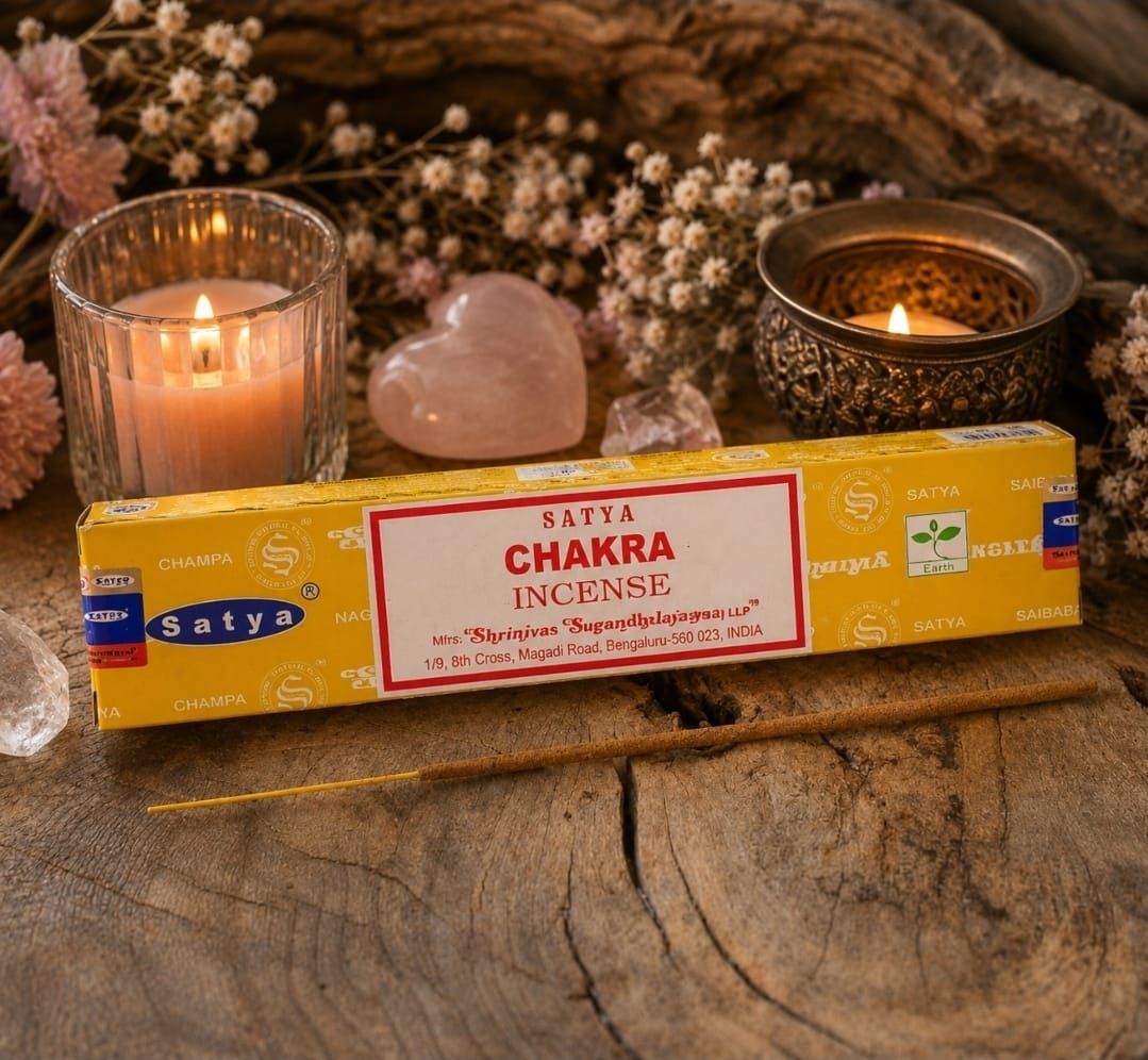 Gele chakra-wierookdoos met kaarsen, kristallen en gedroogde bloemen op een rustieke ondergrond.