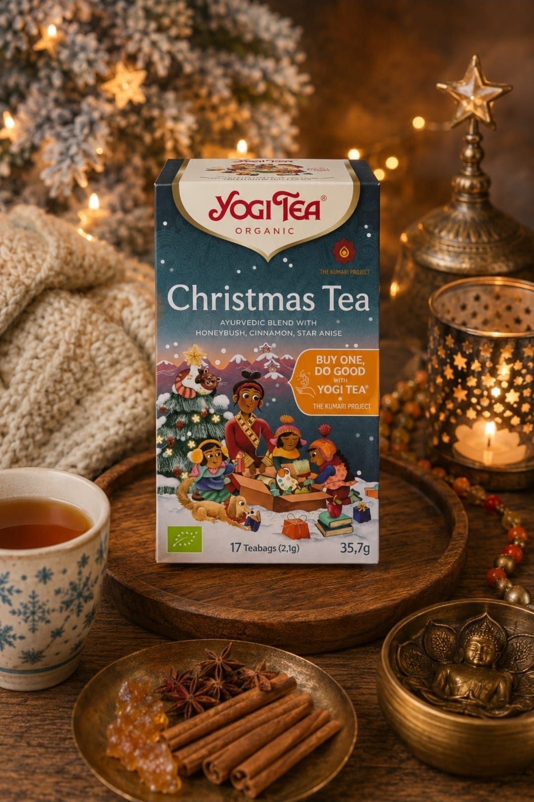 Yogi Tea kersttheebox met theekopje, kaneelstokjes, kaarsen en kerstversiering in een warm licht.