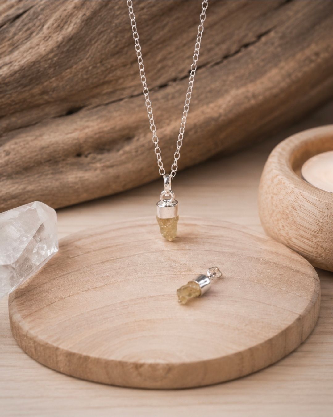 Een delicate kristallen hanger en bijpassende oorbellen, gepresenteerd op een houten dienblad.