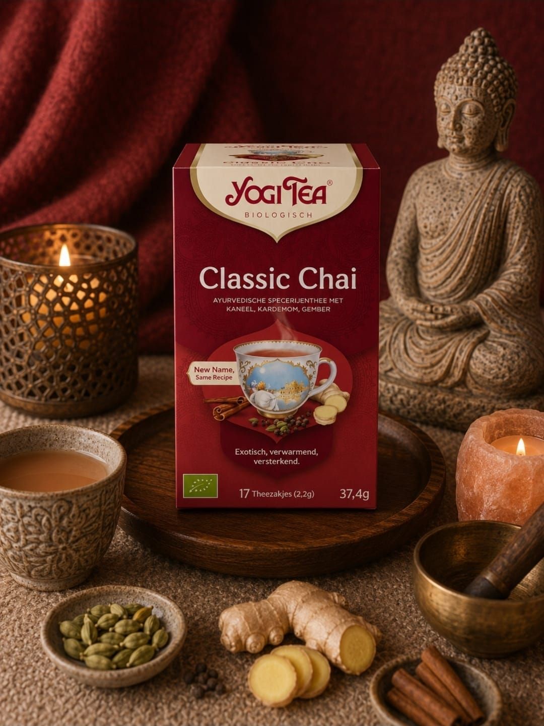 Een doos Yogi Tea Classic Chai op een gezellig tafeltje met kaarsen, theekopjes, kruiden en een Boeddhabeeld.