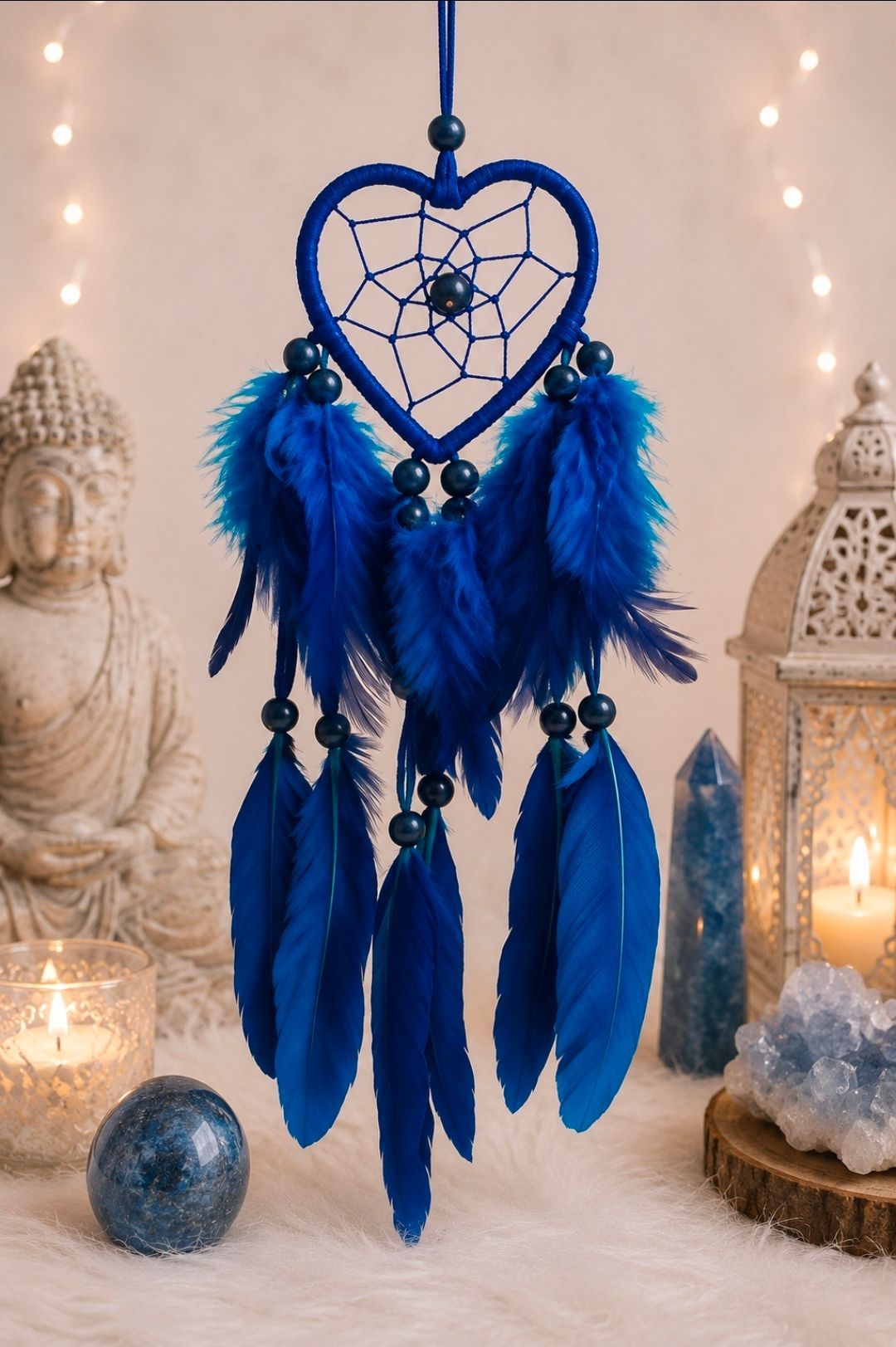 Een blauwe, hartvormige dromenvanger met veren die tussen gloeiende kaarsen en lantaarns hangen.