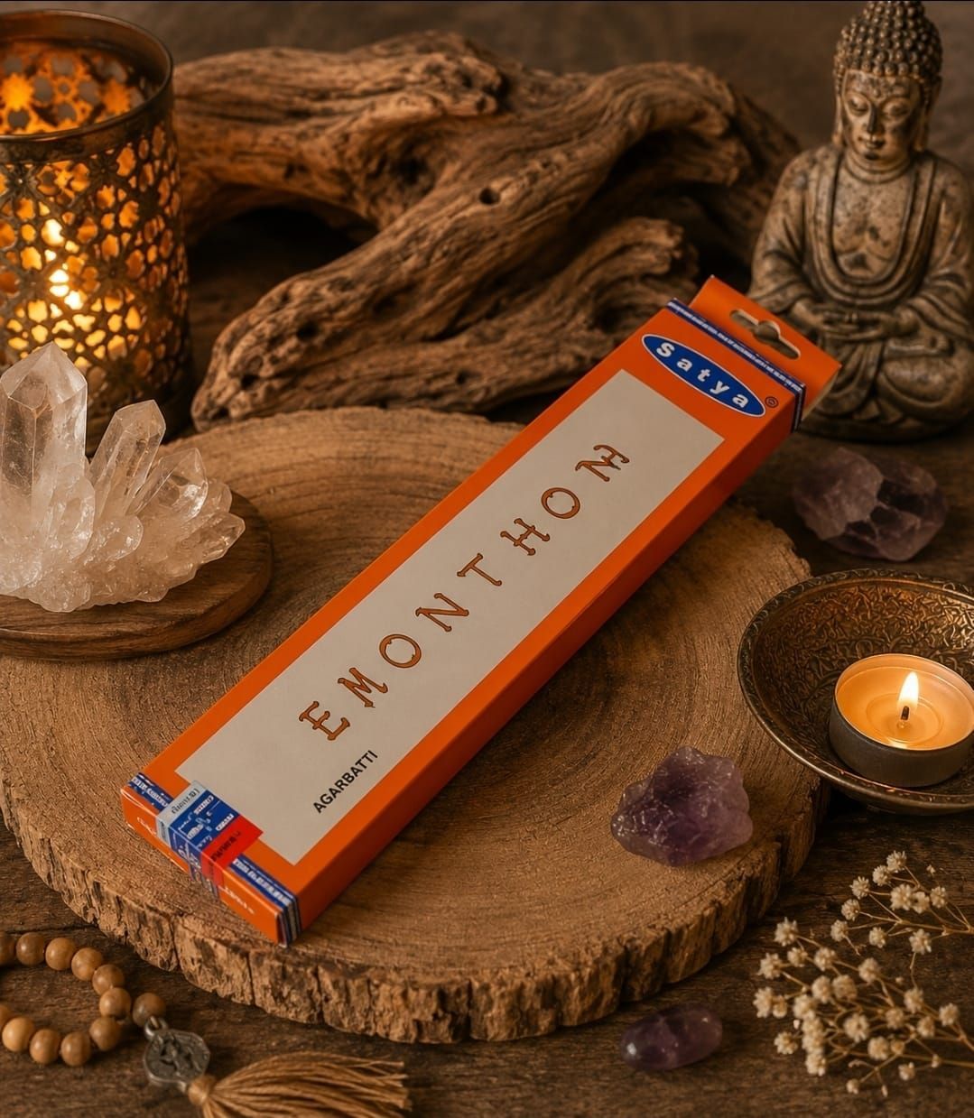 Een doosje oranje Emonhor wierook op een rustiek altaar met kaarsen, kristallen, drijfhout en een Boeddhabeeld.