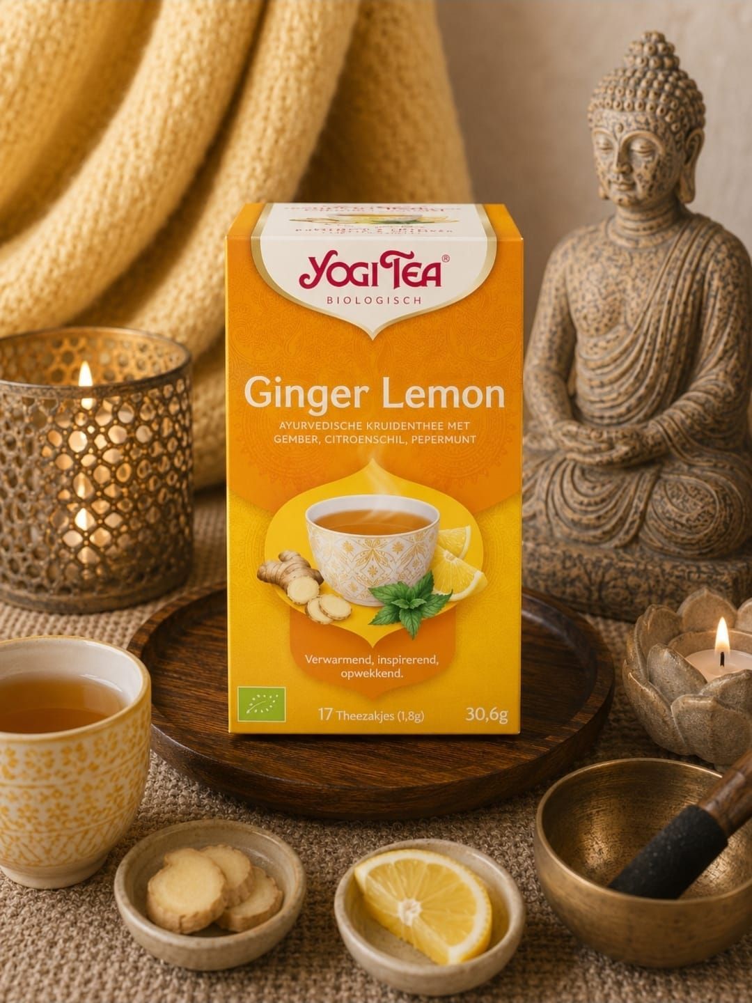 Yogi Tea Ginger Lemon doos met citroentheekopje, gember en citroenen, gepresenteerd op een warme tafel.
