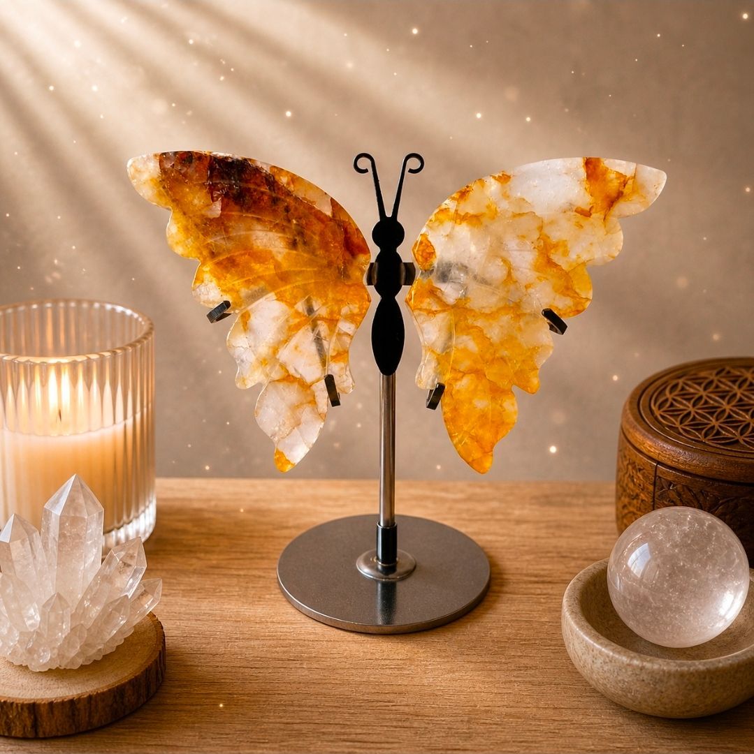 Een sculptuur van een vlindervleugel op een sokkel, verlicht door kaarsen en kristallen op een warme houten tafel.