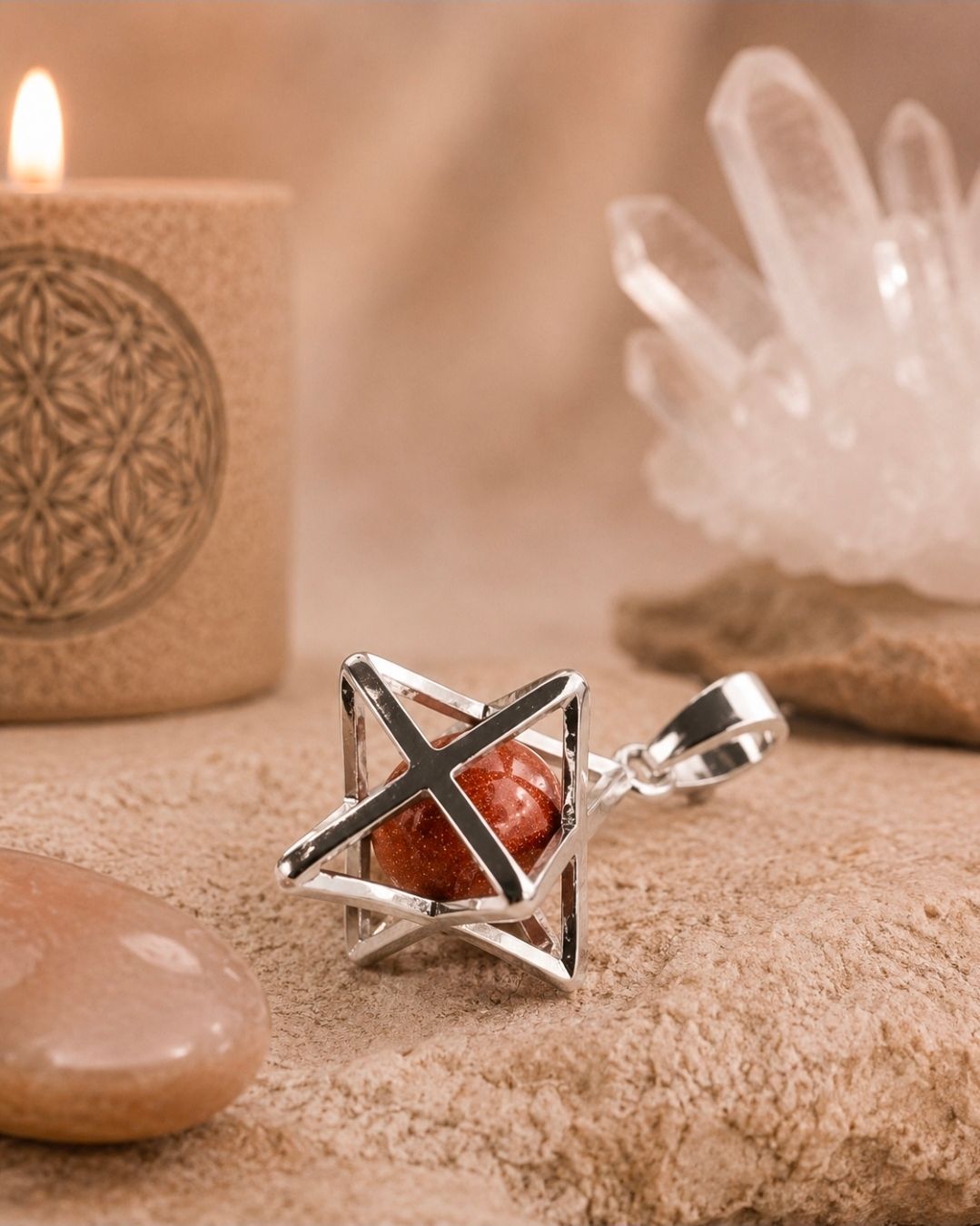 Zilveren geometrische ring met een rode steen op een zachtbeige ondergrond, naast kristallen en een brandende kaars.