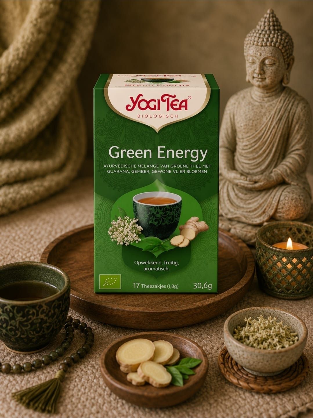 Een doos Yogi Tea Green Energy met een theekopje, gember en een Boeddhabeeldje op een warme, rustieke tafel.