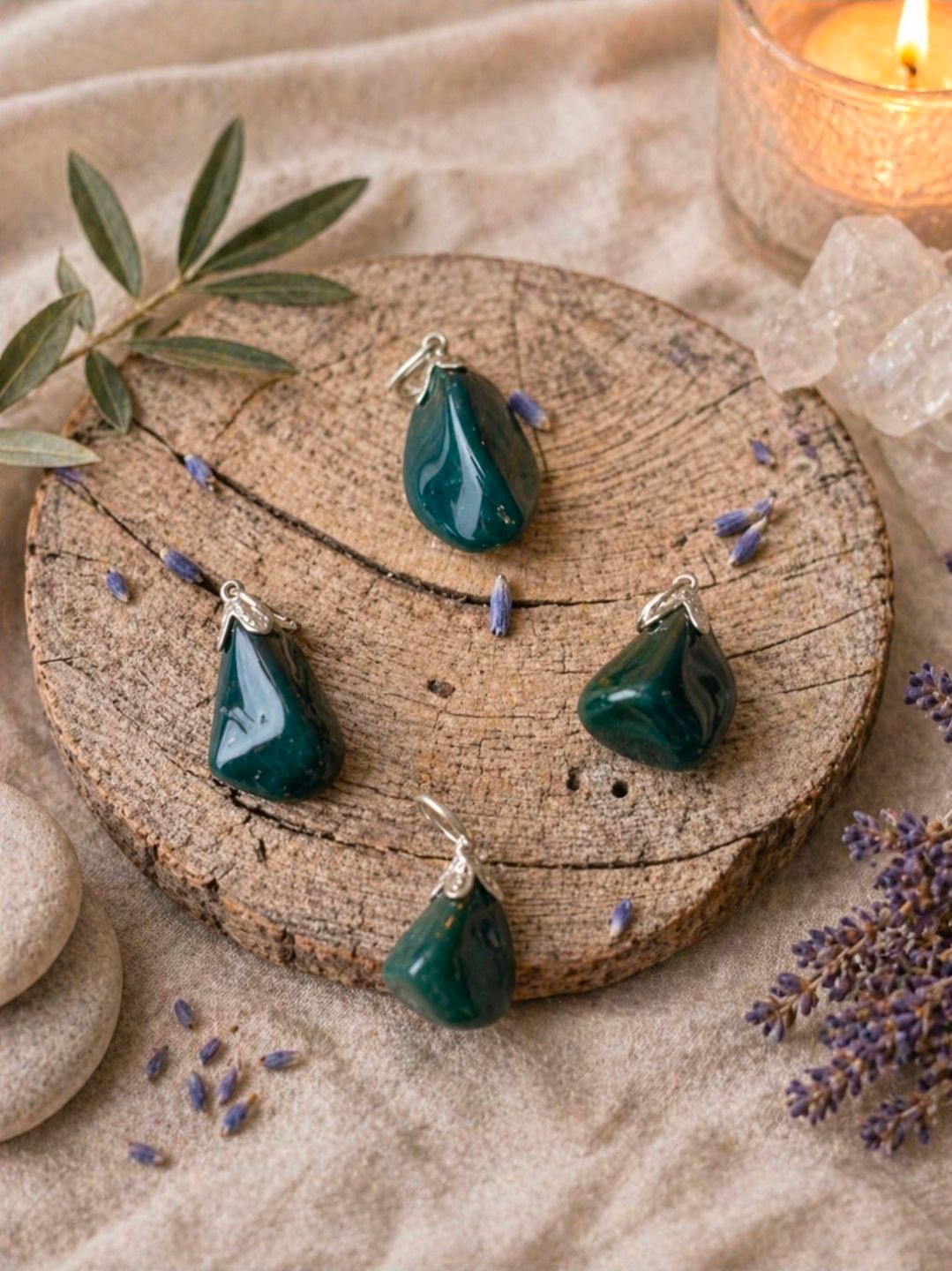 Turquoise hangerkettingen op een rustiek rond houten dienblad met lavendeltakjes en een brandende kaars.