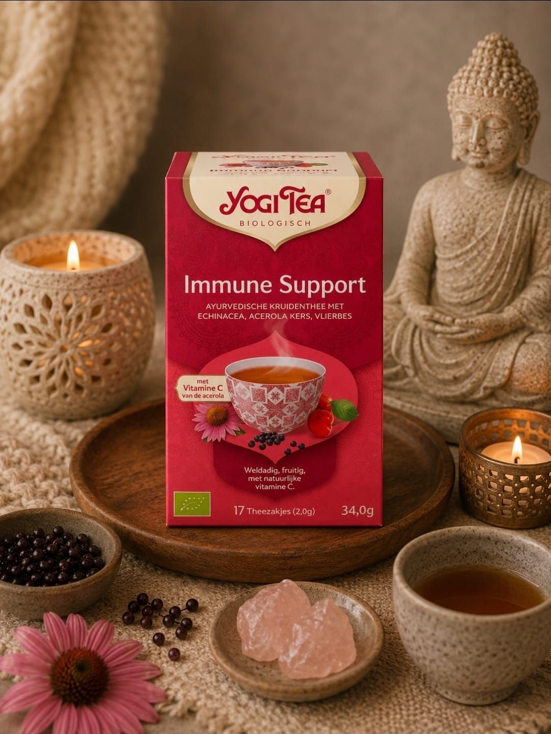 Een doos Yogi Tea Immune Support op een spa-achtige tafel met kaarsen, een Boeddhabeeldje, een theekopje en bloemen.