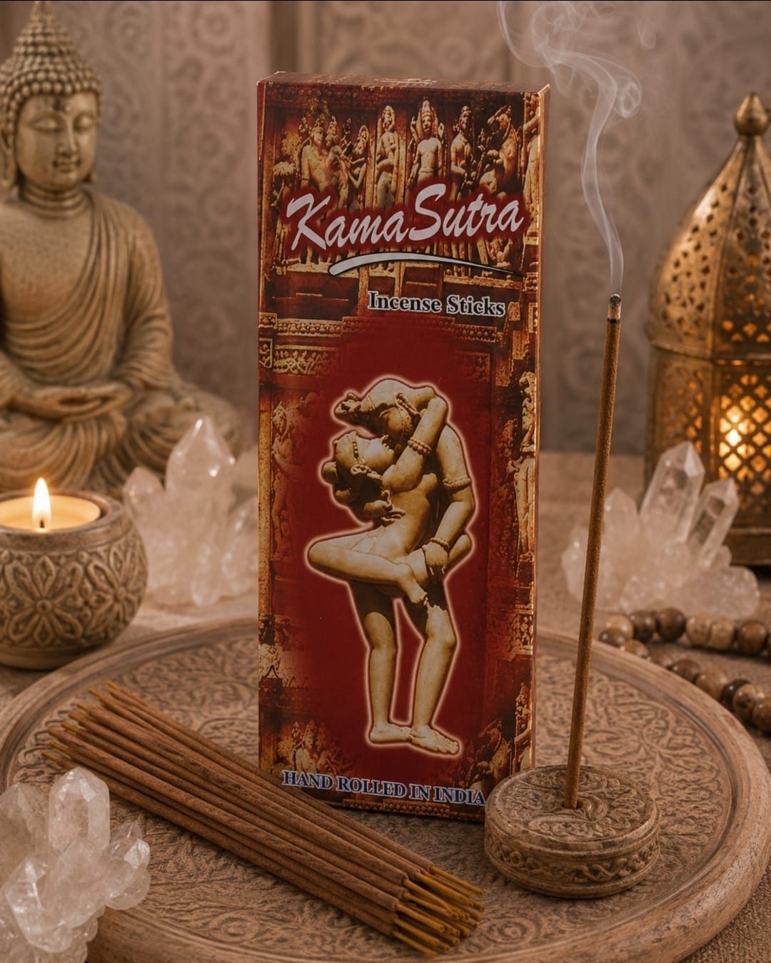Een rood doosje met Kamasutra-wierook op een dienblad met een brandende kaars, wierookstokjes, kristallen en Boeddha