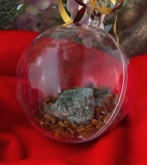 Glazen bolvormig terrarium met groene kristallen en bruine stenen erin.