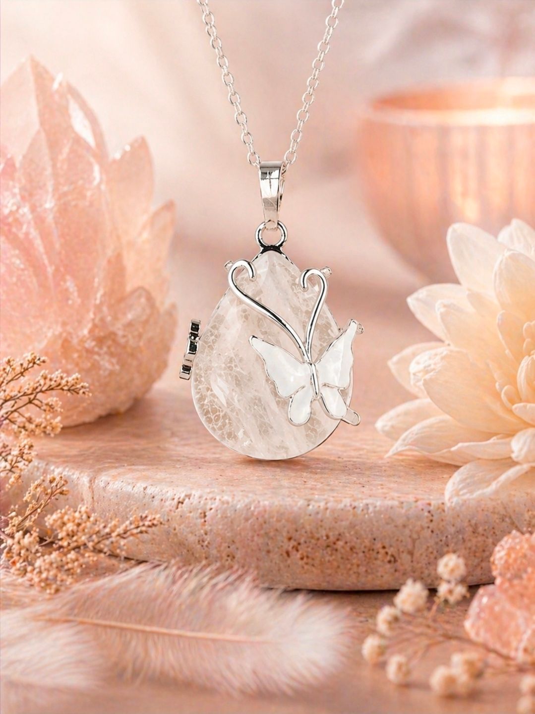 Zilveren vlinderhanger aan een delicate ketting, afgebeeld op een zachtroze bloemenachtergrond.