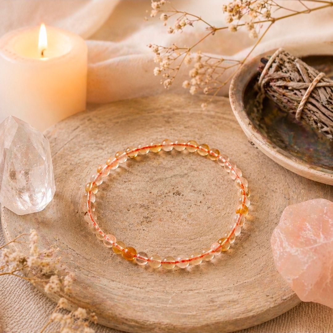Kristallen armband op een houten dienblad met kaarslicht, rozenkwarts en gedroogde bloemen.