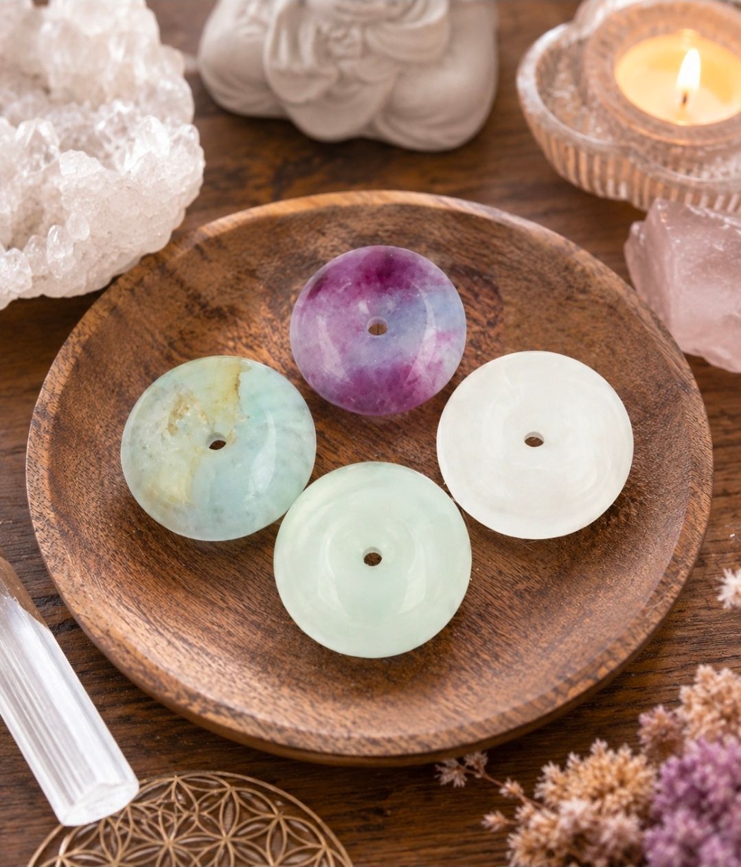 Pastelkleurige ronde kaarsen op een houten schaal met kristallen en een brandende kaars ernaast.