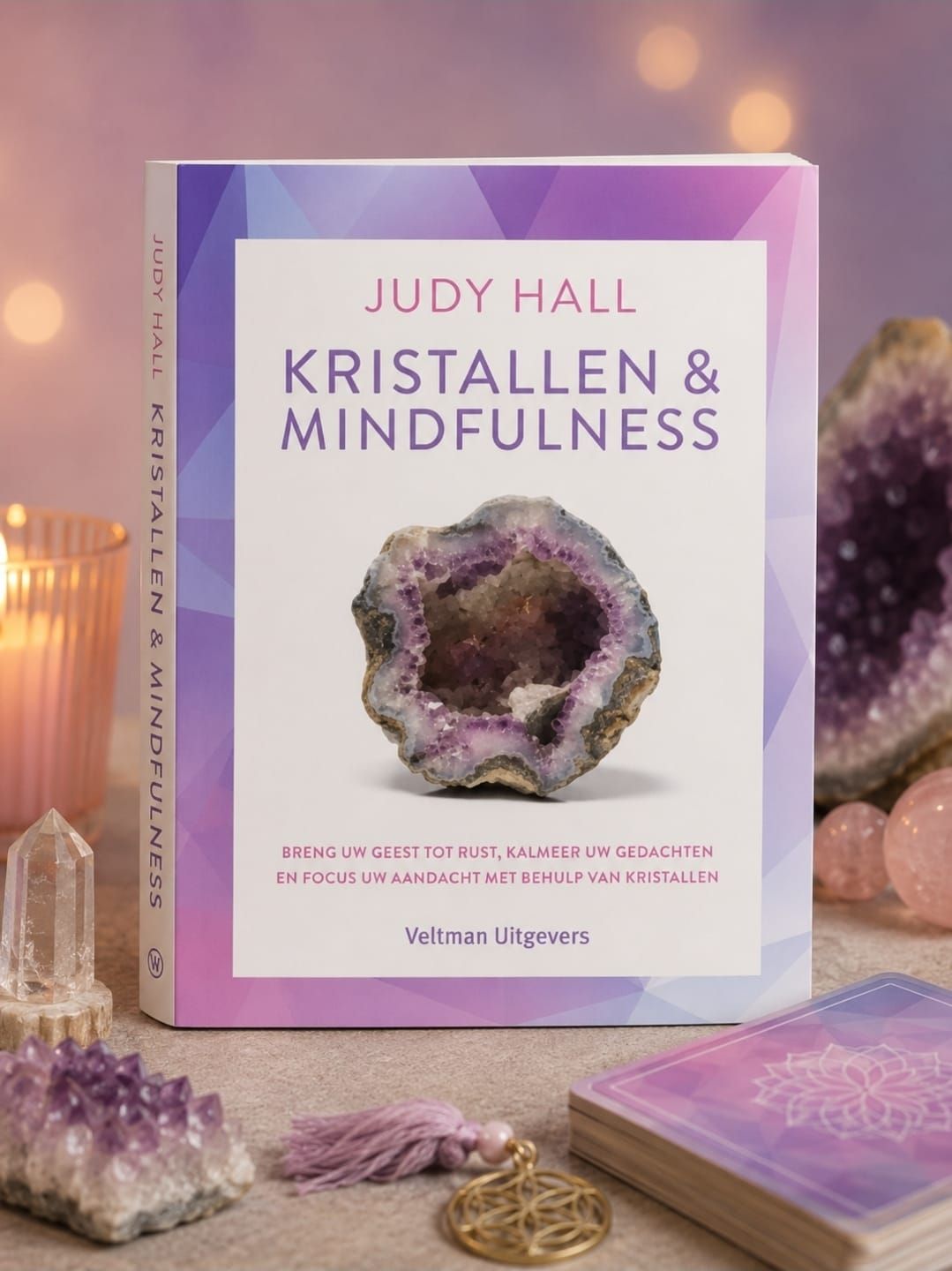 Boekcover voor “Kristallen & Mindfulness” van Judy Hall met een paars kristal op een pastelkleurige achtergrond.