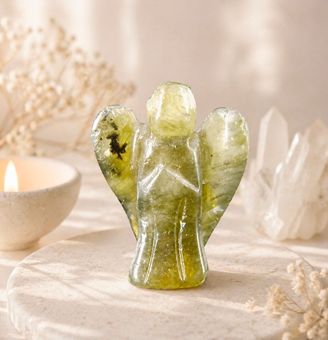 Klein groen kristallen engeltje met uitgestrekte vleugels op een zacht verlicht tafelblad.