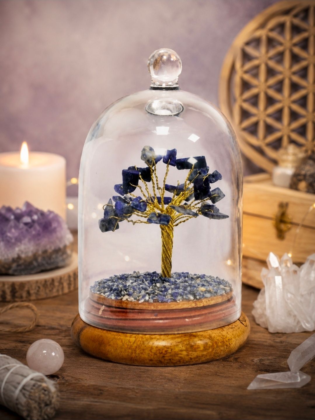Kristallen bol met een blauwe edelstenenboom op een houten voet, omringd door kaarsen en kristallen.