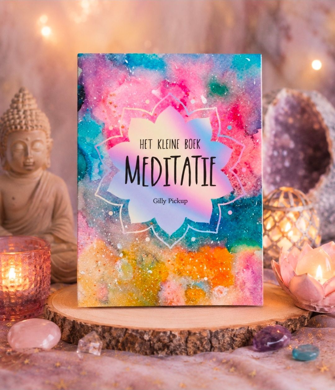 Kleurrijke omslag van een meditatieboek met een Boeddhabeeld en glinsterende kristallen op een zachtroze achtergrond.