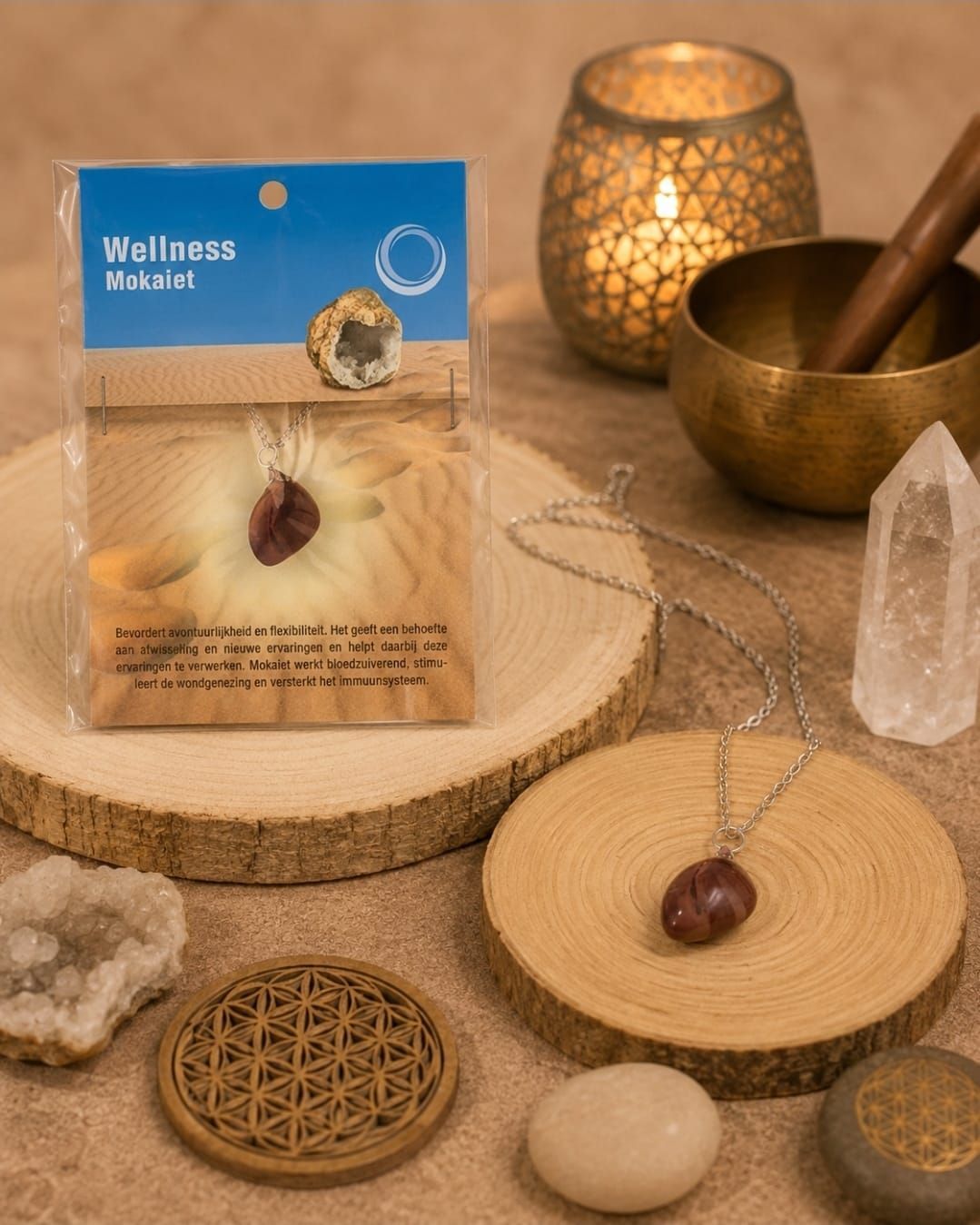 Wellnesspresentatie met hangerketting, kristal, klankschaal, kaars en decoratieve stenen op een houten tafel.