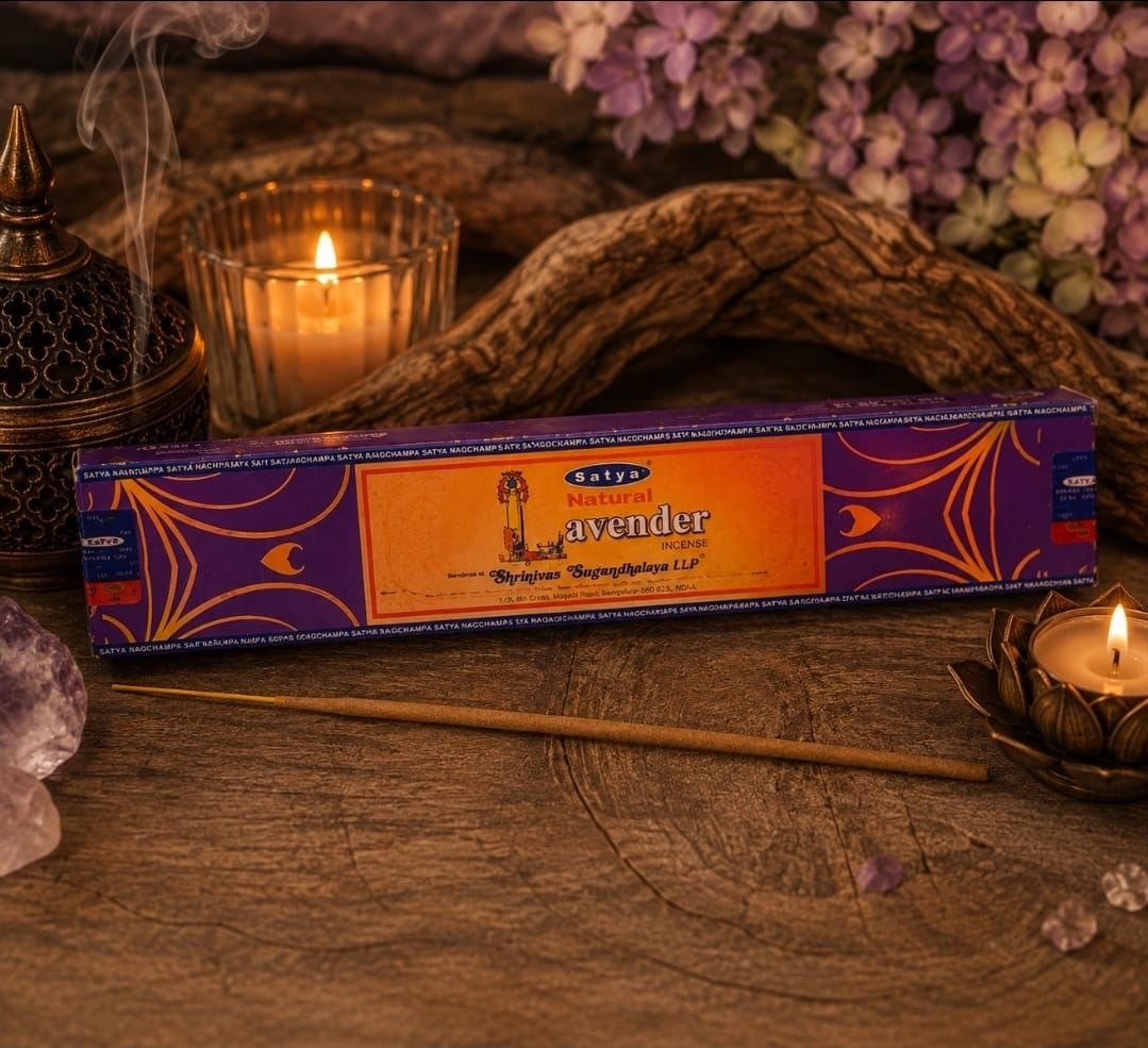 Paarse wierookdoos op een houten tafel met brandende kaarsen en bloemen op de achtergrond.